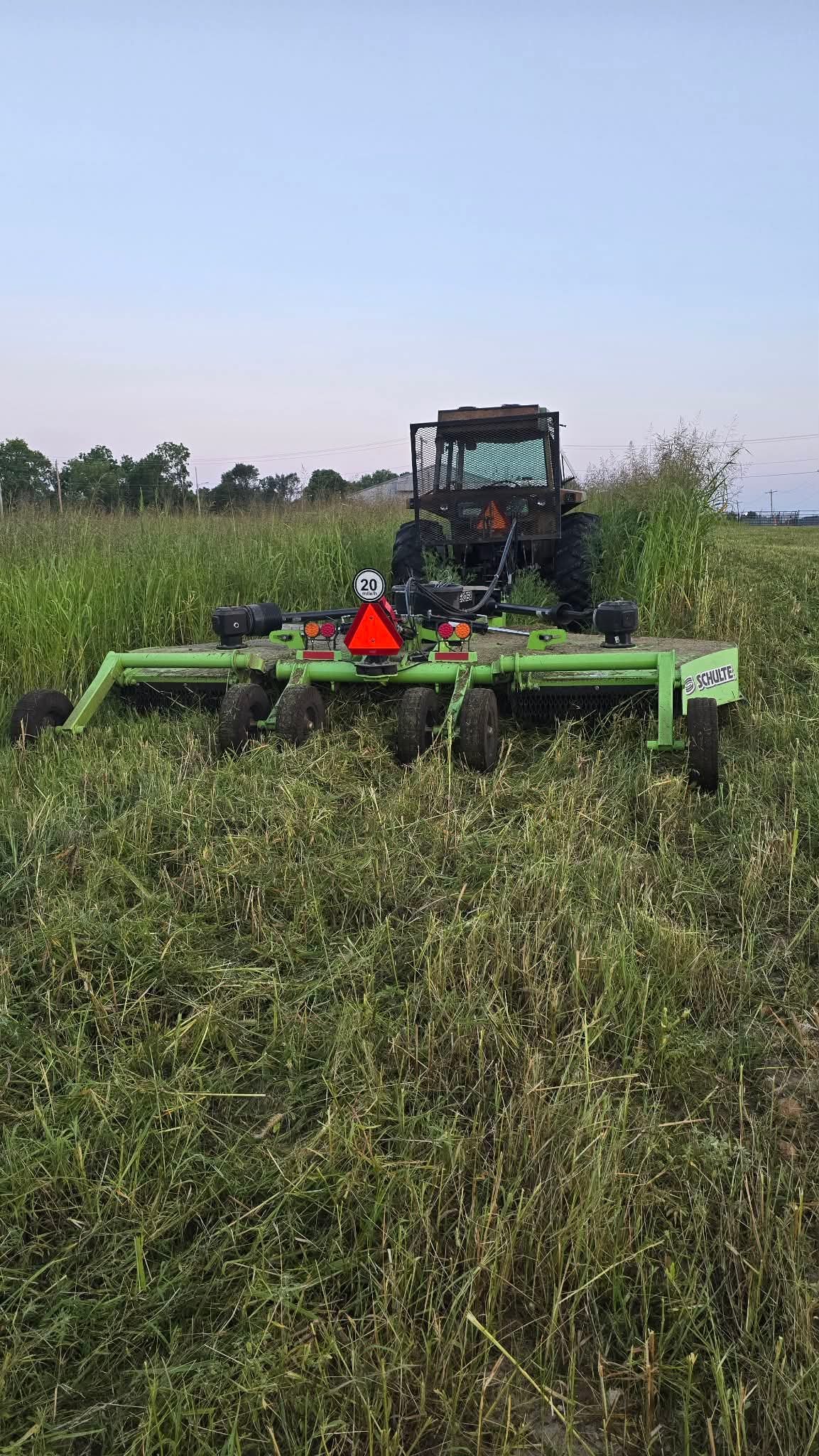 Schulte rotary cutter behind the tractor in tall grass
